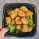 hand holding bowl of beyond orange chicken